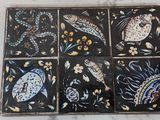 une photo d'un lot de quatre sous-verres en carrelage posés sur une table en marbre