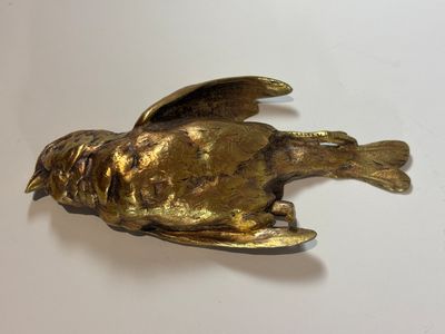 a gold bird that is sitting on a white table