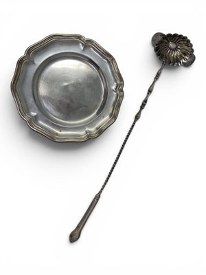 a silver plate and a silver spoon on a white surface