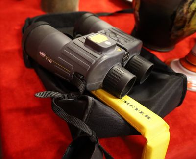 un sac noir muni d'une poignée jaune et sur lequel est posé un paire de jumelles