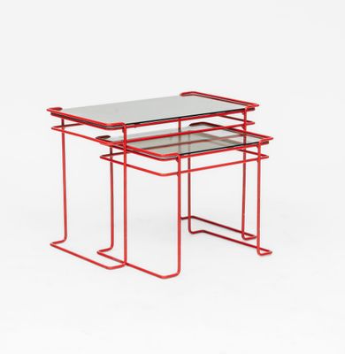 une paire de tables en métal rouge avec des plateaux en verre, sur fond blanc