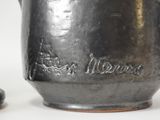 a silver vase with writing on it next to some rocks