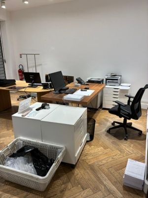 une pièce dans laquelle se trouvent un bureau, une chaise, un ordinateur et une poubelle