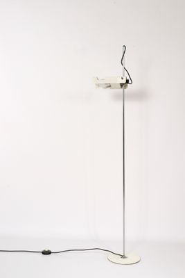 un lampadaire blanc posé sur un sol blanc, à côté d'un mur blanc