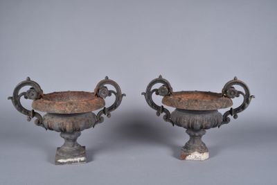 pair of antique cast iron urns on pedestals on grey background