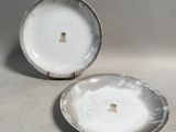une paire d'assiettes blanches et argentées ornées de motifs dorés