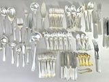 a lot of silver spoons and forks hanging on the wall