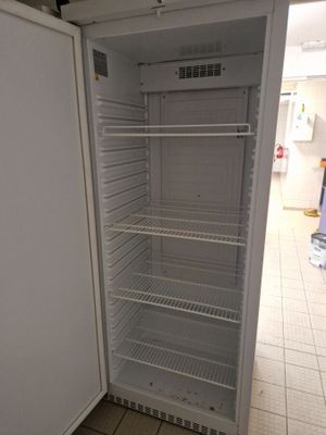 un réfrigérateur vide au milieu d'un sol carrelé