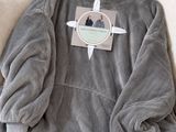 une couverture posée sur un canapé, avec un sweat à capuche posé dessus