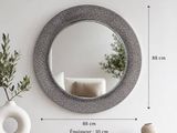 un miroir accroché au mur, à côté d'un vase contenant une plante