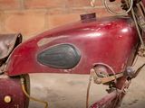 an old red motorcycle with a leather seat and saddle