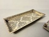a silver tray with a design on it next to a candle