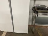 two white refrigerators in a room next to a chair