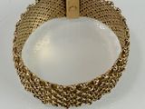 a close up of a gold bracelet on a white surface