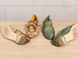 three pairs of shoes sitting on top of a wooden table