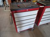 two red and white drawers with tools on them in a garage