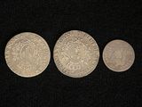 three silver coins sitting next to each other on a black surface
