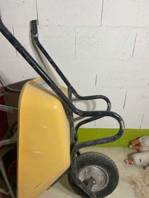 a yellow wheelbarrow with a black handle on the floor