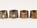 a group of four brass napkins with designs on them