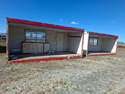 un vieux bâtiment rouge et blanc situé au milieu d'un champ d'herbe sèche