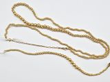 un gros plan d'un collier de perles dorées posé sur une surface blanche