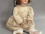 an antique doll sitting on the ground with a hat on