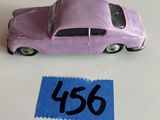 une petite voiture violette posée sur une feuille de papier bleue