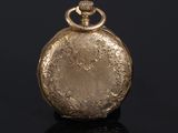 an antique gold pocket watch on a black surface with a black background