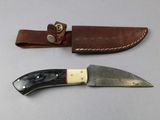 a knife that is sitting next to a leather sheath