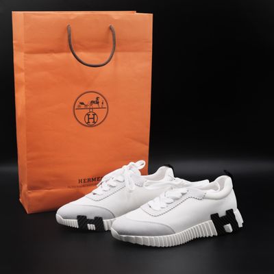 a pair of white sneakers next to a shopping bag
