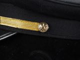 a close up of a uniform hat with a gold stripe