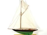 une petite maquette de voilier posée sur un socle jaune