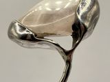 a close up of a silver spoon with a white stone on it