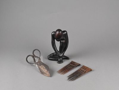 une paire de ciseaux, des peignes et une sculpture posée sur une table