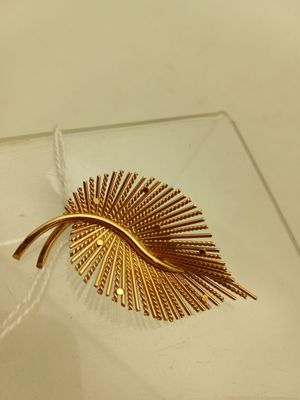 une broche en feuille d'or posée sur une assiette en verre transparent