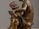 bronze statue of a woman reading a book to a child on a stool