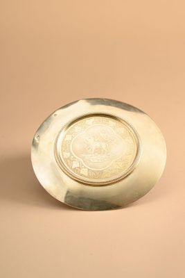 an image of a silver plate with a medallion on it