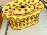une assiette jaune ornée d'un motif floral, à côté d'un panier rempli de fleurs