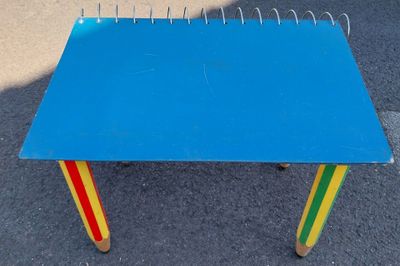 une petite table bleue avec des pieds de différentes couleurs