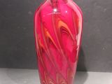 un vase en verre rose orné d'un motif rouge en spirale