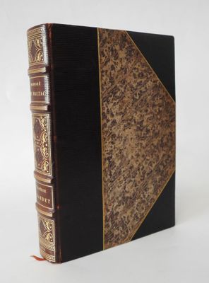 an old book with a black cover and gold trim on a white background