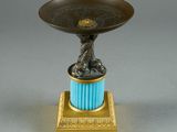 a gold and blue vase with a bird on top of it