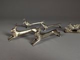 three silver figurines of a dog and a cat on a table