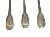 three silver spoons with designs on them sitting next to each other