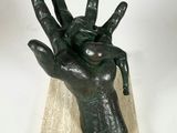 statue of a hand holding a ball on a wooden base