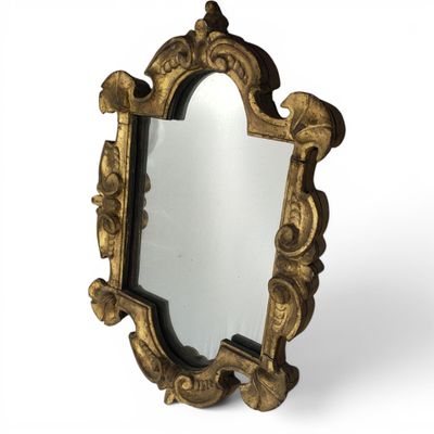 an ornate gold mirror with a black frame and a white background