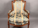 une vieille chaise dont l'assise est recouverte d'un tissu bleu et or