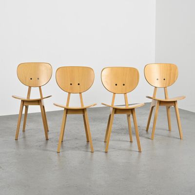 trois chaises en bois dans une pièce au sol en béton et aux murs blancs