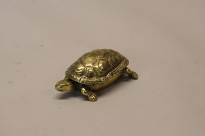 une petite tortue en or posée sur une table