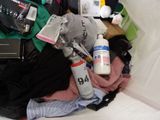 a pile of clothes and a bottle of water on a bed